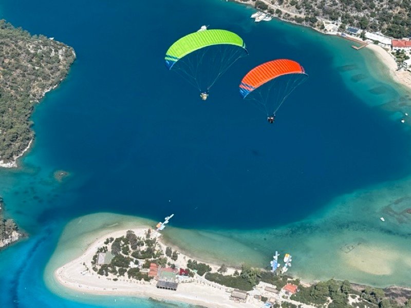 Ölüdeniz lagünü üzerinde yeşil ve turuncu kanatlarla uçuş